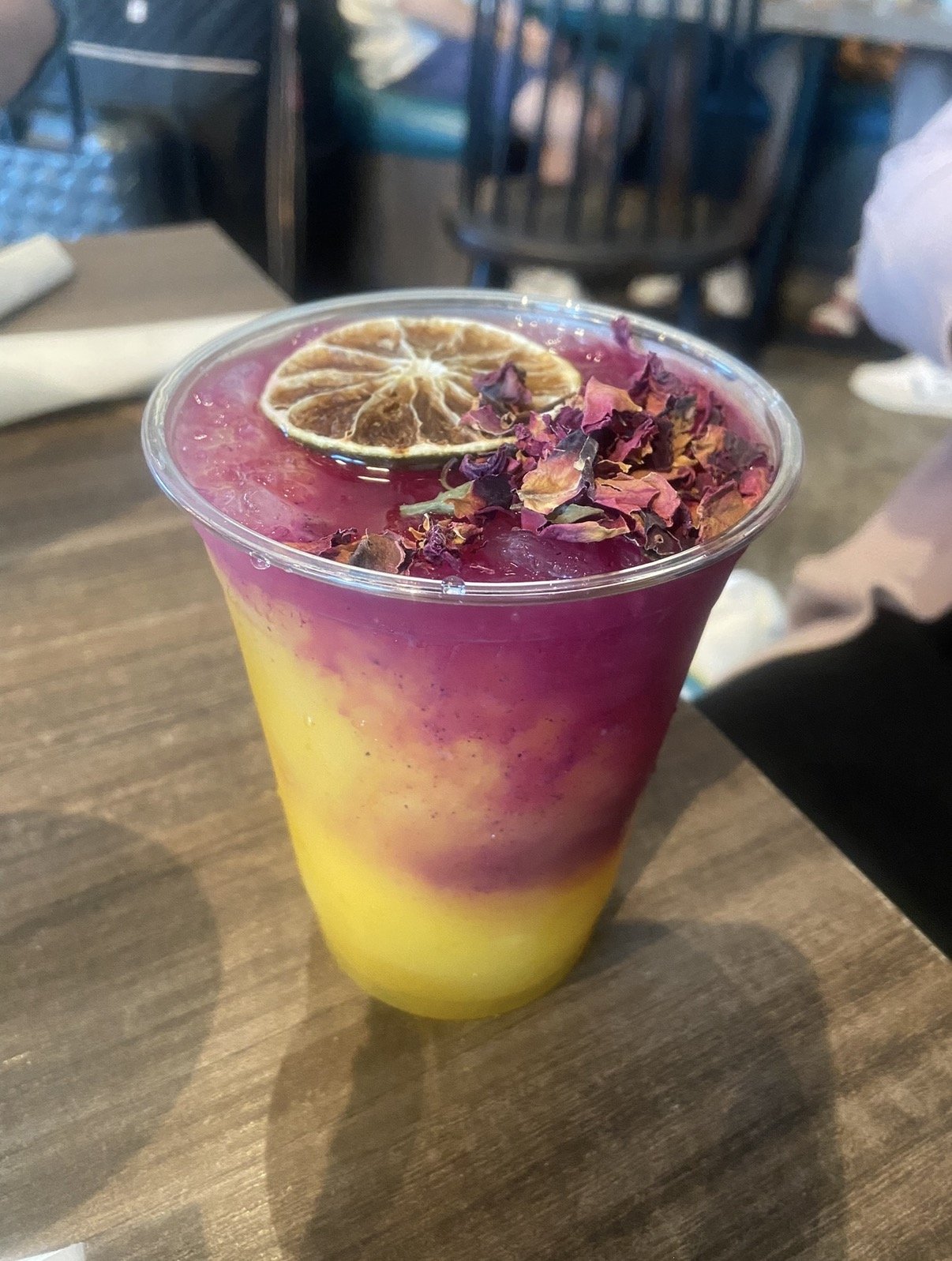 Vibrant pink and yellow cocktail topped with dried rose petals and a lime wheel