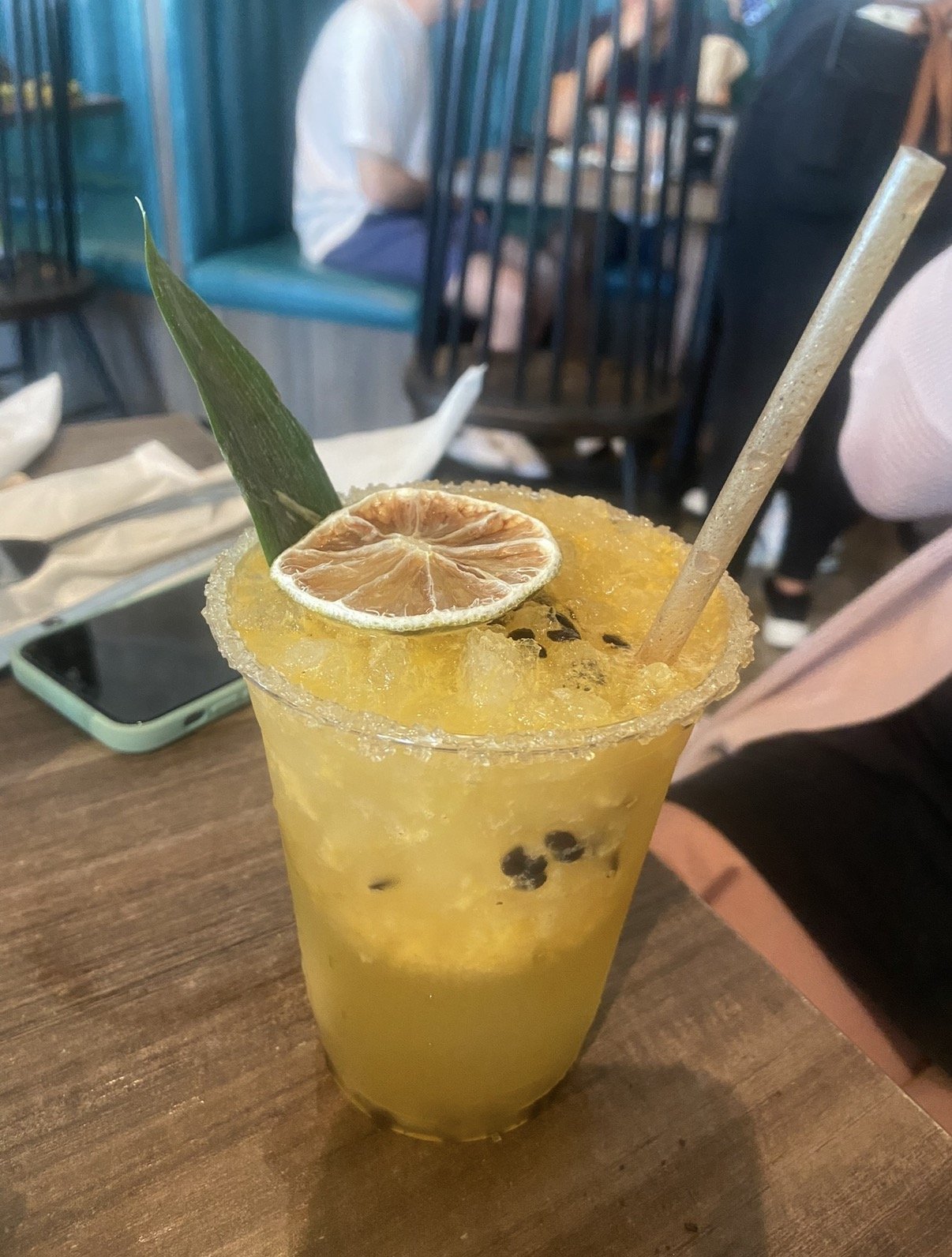 Passion fruit cocktail with sugared rim, dried lime wheel, and pineapple leaf garnish