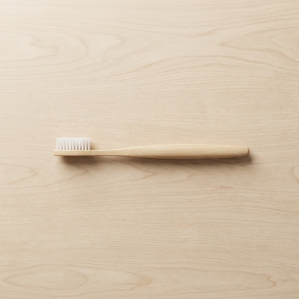 Bamboo toothbrush with light wood handle on light wood surface
