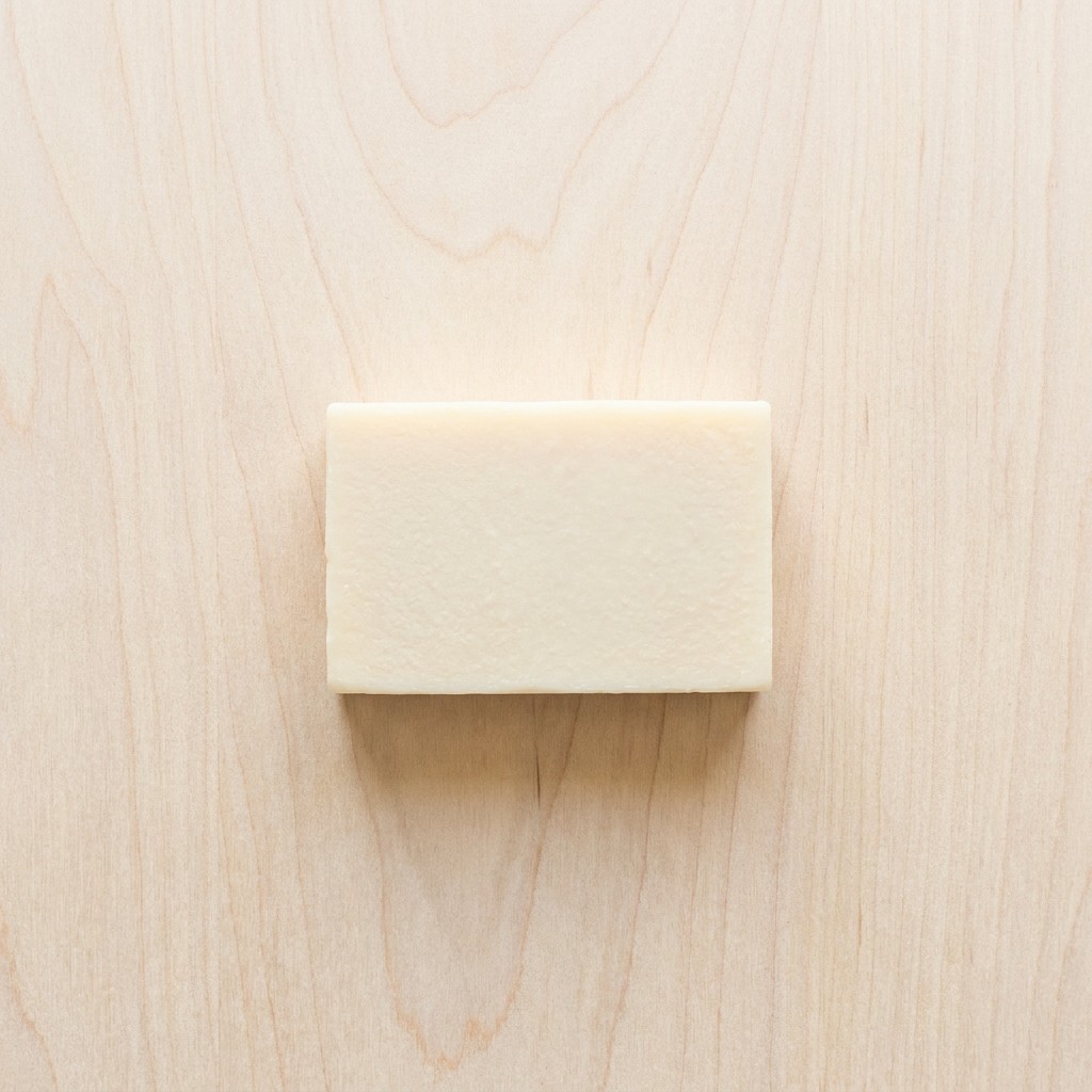 French milled bar soap flat lay on light wood surface